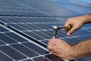 Man worker installing solar photovoltaic panels on roof, alternative energy concept.
